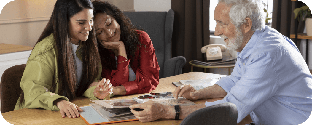 Un moment de complicité et de partage de souvenirs entre un bénéficiaire et deux intervenantes du Connétable, illustrant la lutte contre l'isolement à domicile.